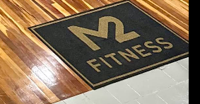Tapete com o logo da M2 Fitness na entrada da academia